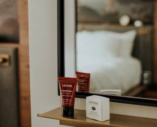 a tube and small box on a shelf before a mirror